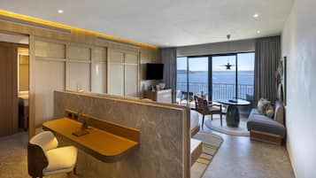 Habitación de hotel moderna con zona de estar, una mesita, sofá y un gran ventanal con vistas al mar.