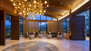 A spacious lobby with a modern chandelier, tiered seating, and large windows offering a view of the outdoors. - Waldorf Astoria Costa Rica Punta Cacique (Sardinal)