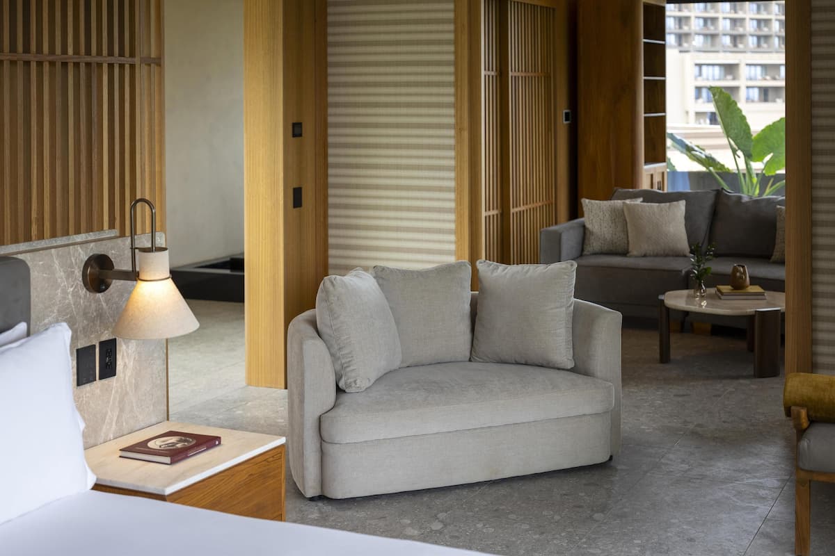 A modern hotel room with a sofa, a small table, and a lamp.