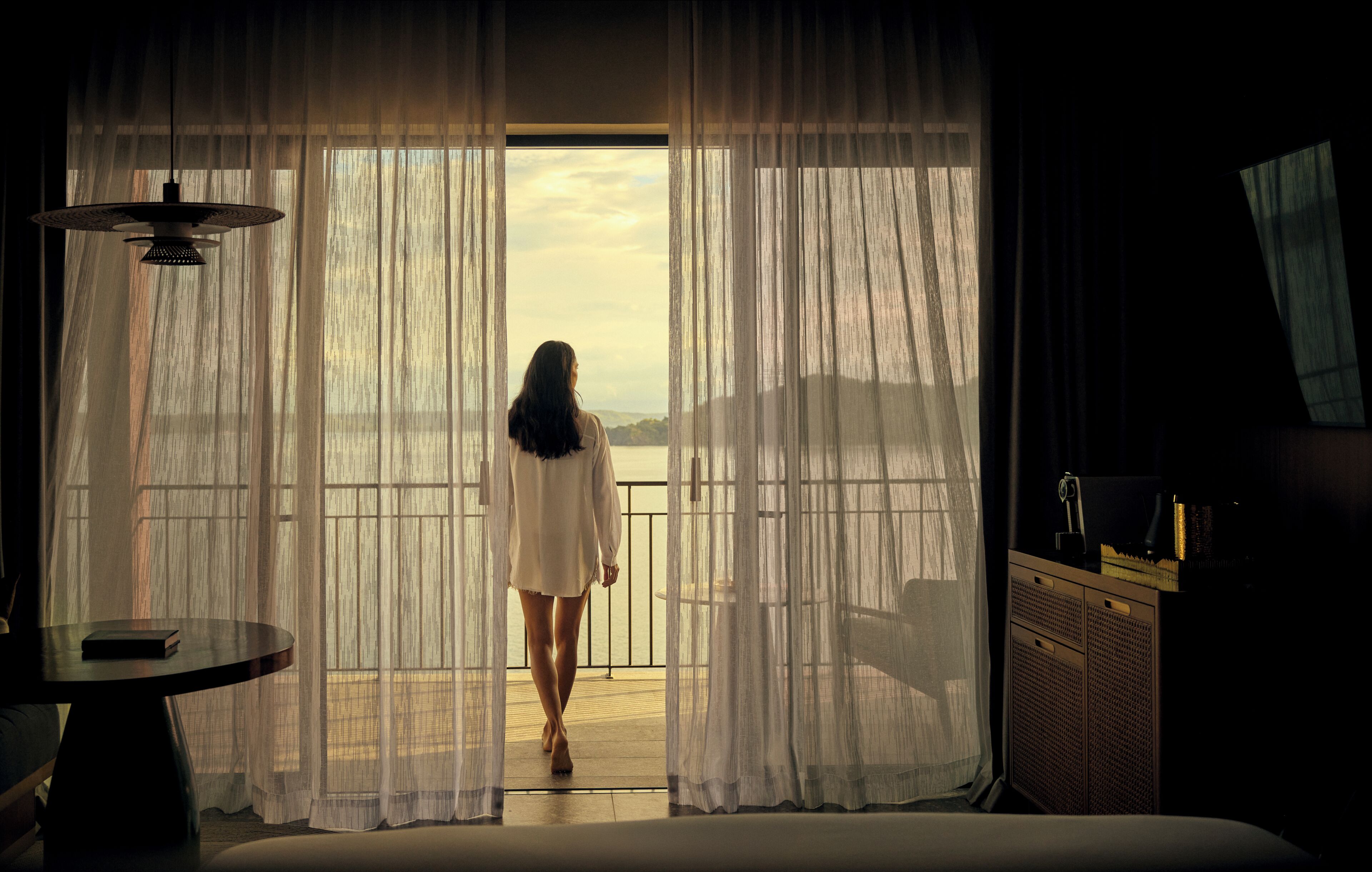 A room with a large window, a bed, a table, and a chair.