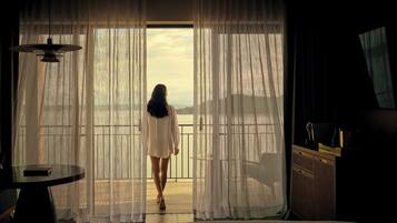 A room with a large window, a bed, a table, and a chair.