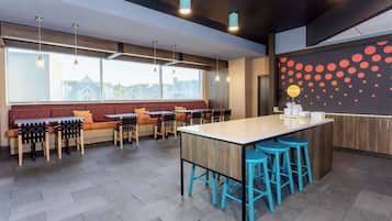 A modern kitchen with a central island, bar stools, and a seating area with a sofa and chairs.