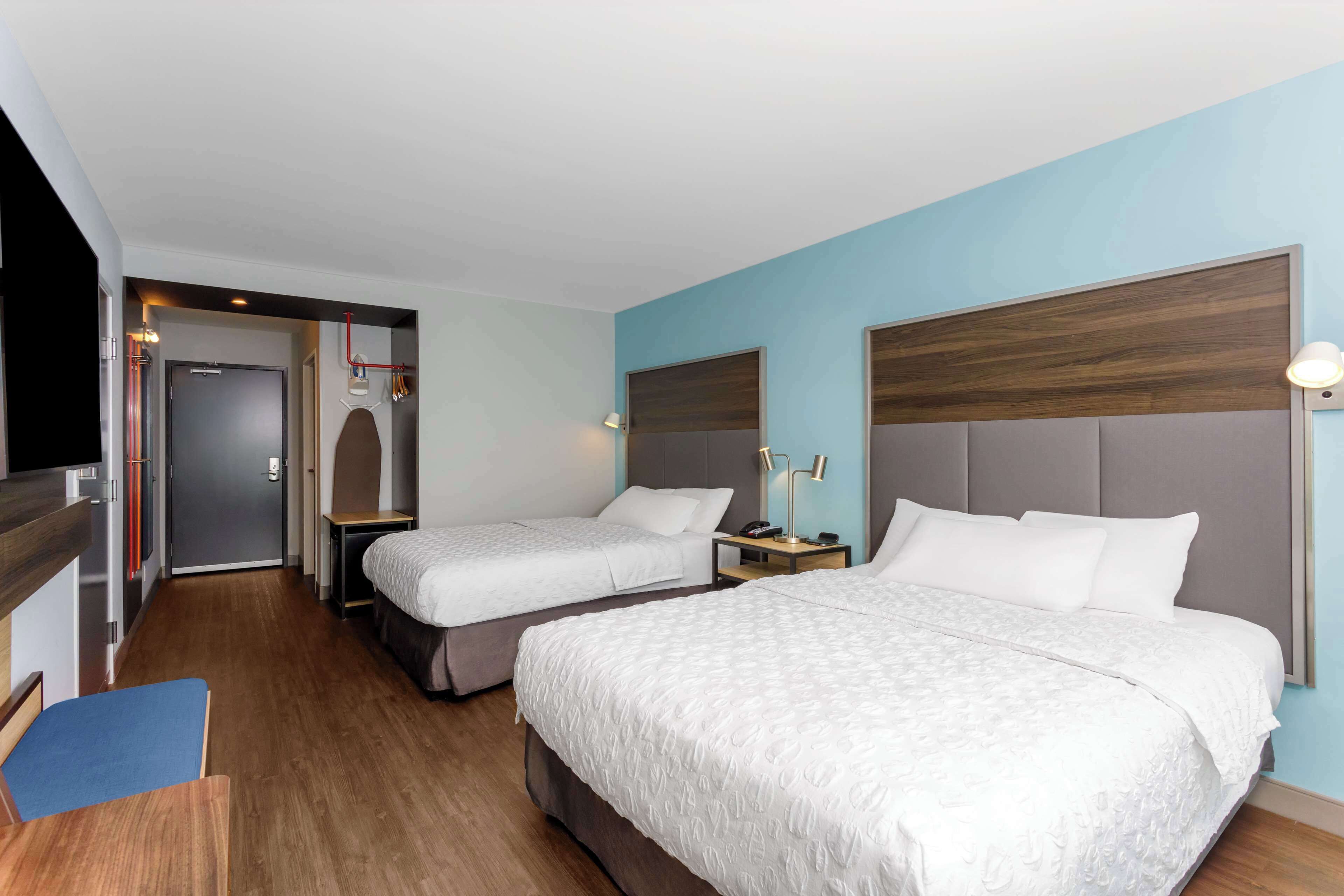 A hotel room with two beds, a desk, and a chair.