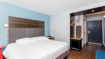 Una habitación de hotel moderna con una cama grande, una mesita de noche, una silla roja y un armario con espejo.