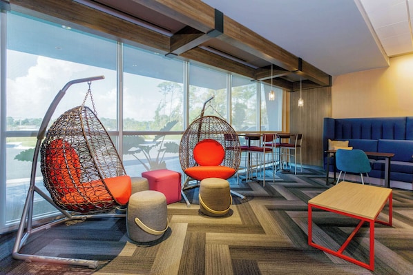 Moderni oleskelualue, jossa on suuri ikkuna, riipputuoli, pehmustettu istuin, pieni pöytä ja sohva.
