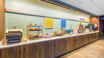 A breakfast bar with a coffee machine, a display case with pastries, and a sign for 'Top 10 Breakfasts'.