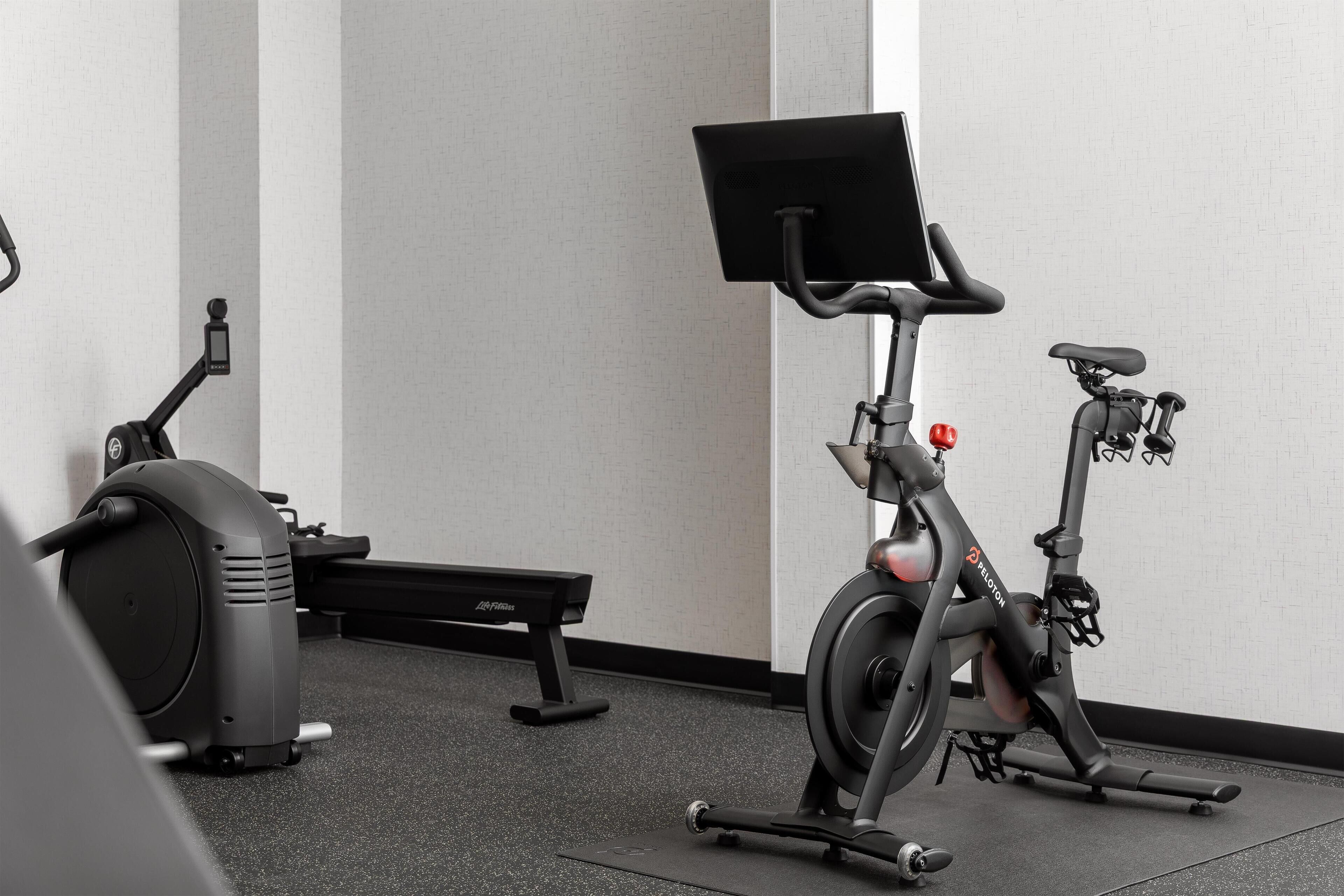 Una bicicleta estática con pantalla y un banco en un gimnasio.