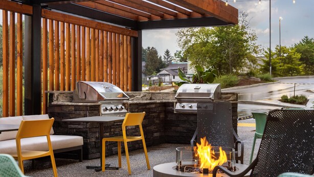 Un patio exterior con asientos de piedra, dos parrillas de barbacoa y un hogar para fuego.