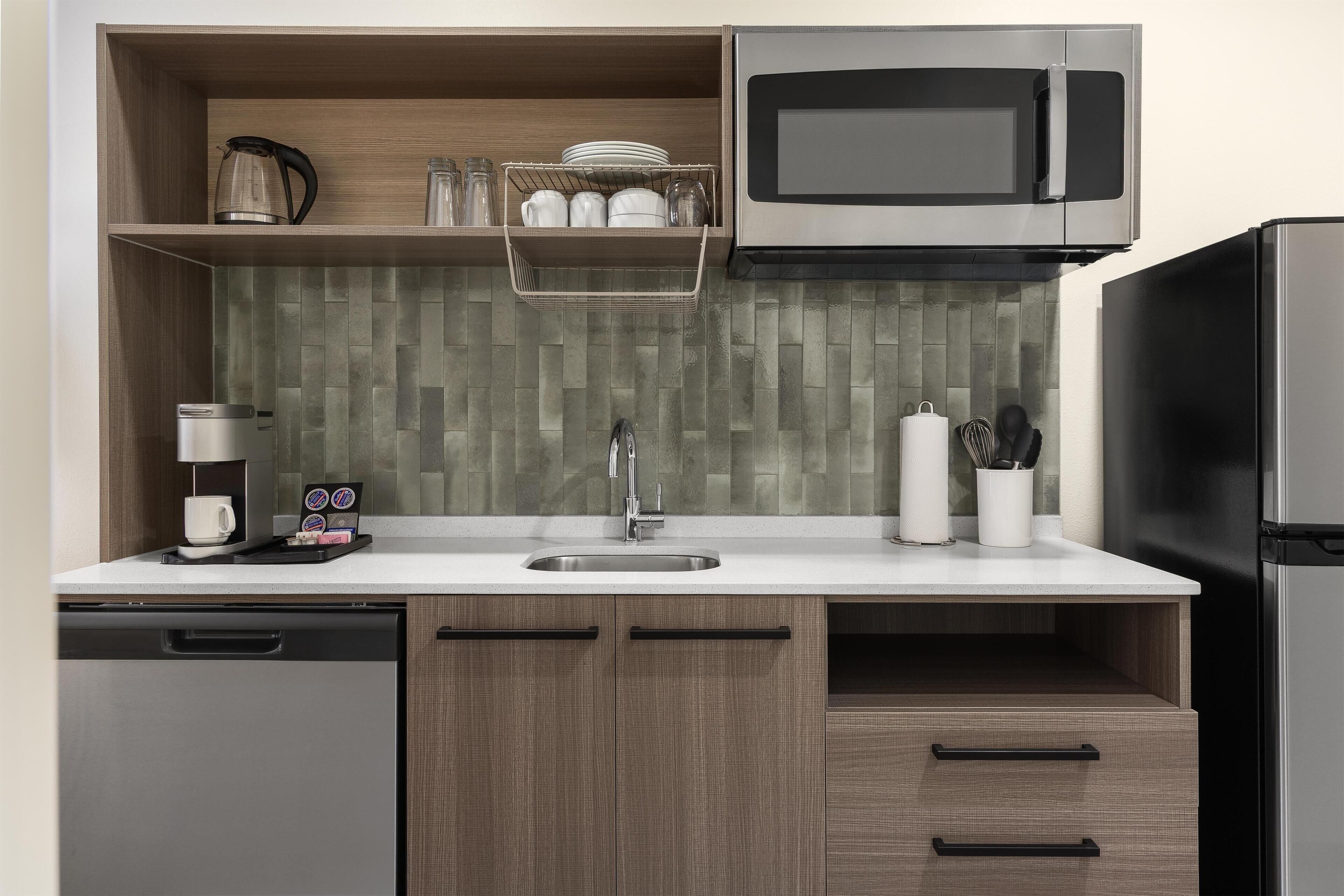 Una cocina compacta equipada con microondas, cafetera y refrigerador de acero inoxidable.