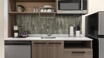 Una cocina compacta equipada con microondas, cafetera y refrigerador de acero inoxidable.