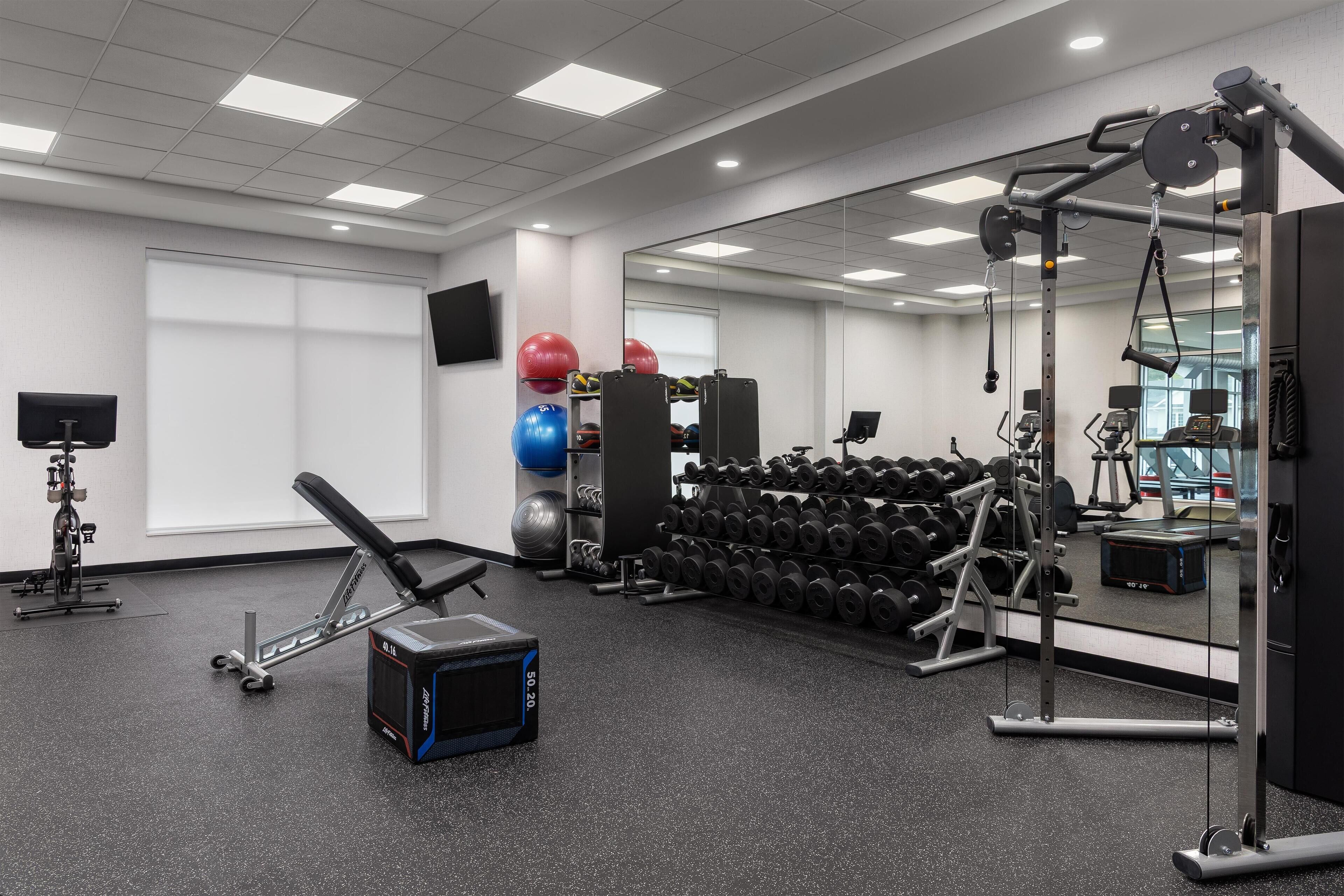 A gym with exercise equipment, weights, and a mirror.