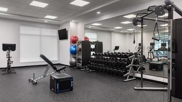 Ein Fitnessstudio mit Trainingsgeräten, Gewichten und einem Spiegel.