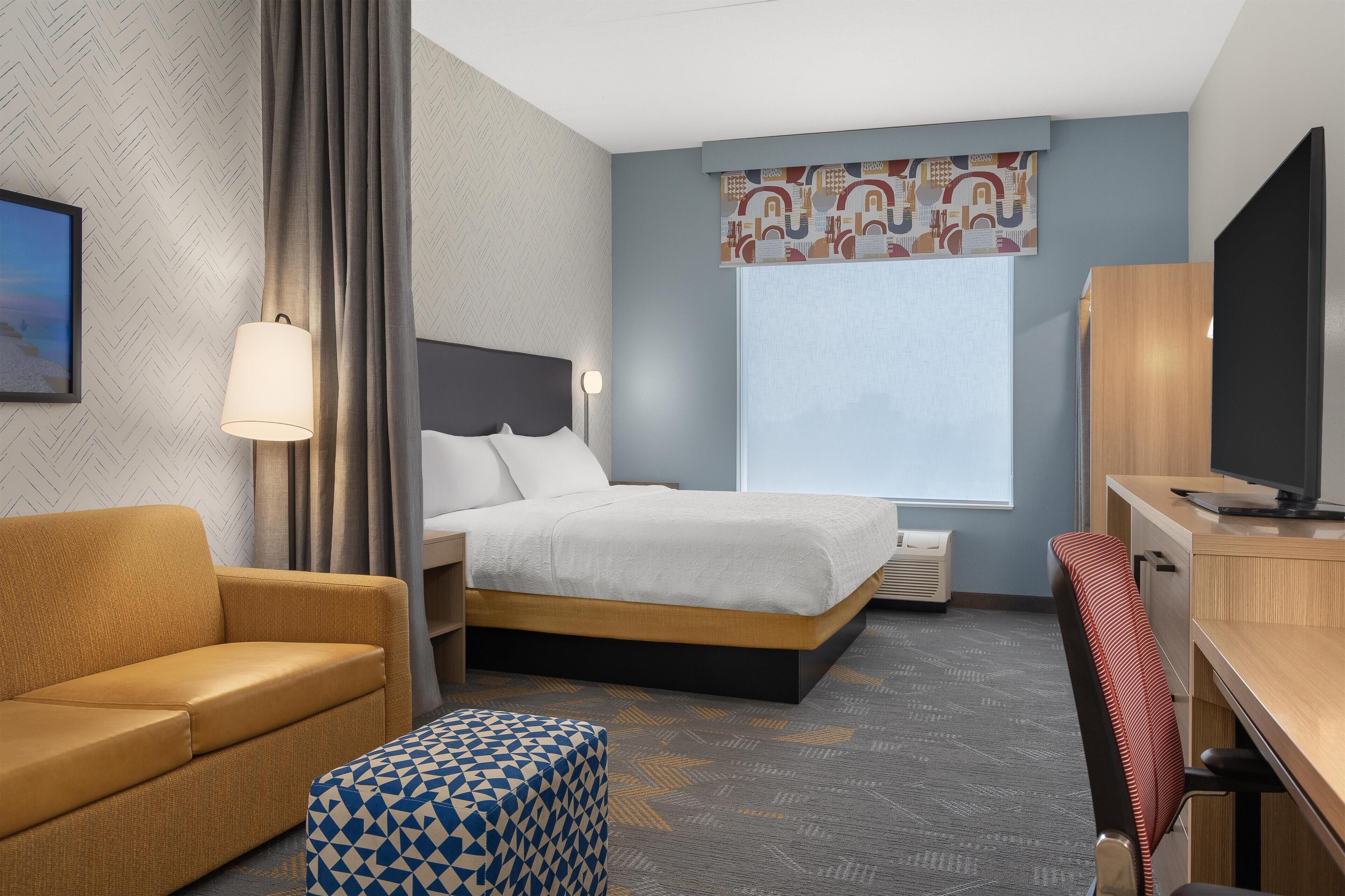 Una habitación de hotel con una cama, un sofá, un escritorio y televisión.