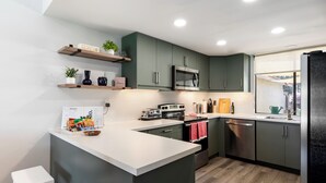 Una cocina moderna con una isla central, electrodomésticos integrados y estantes de madera.