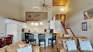 Ein gemütliches Wohnzimmer mit zwei Sofas und einem Couchtisch, ein Küchenbereich mit Esstisch und Stühlen sowie eine Treppe, die zu einer oberen Ebene führt.