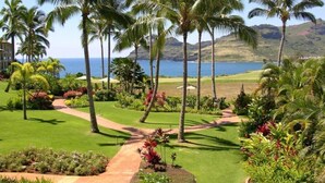 A golf course with palm trees, a pathway, and a view of the ocean.