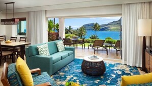 A living room with a sofa, chairs, a coffee table, and a view of the ocean.