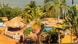Un resort con piscina, palmeras y vista al océano.