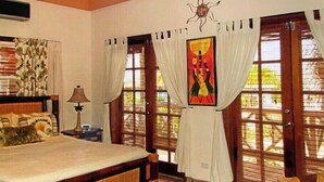 Un dormitorio con cama, cortinas, un cuadro y una ventana.