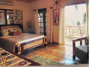 Un dormitorio con cama, una silla, ventana con cortinas y vista al exterior.