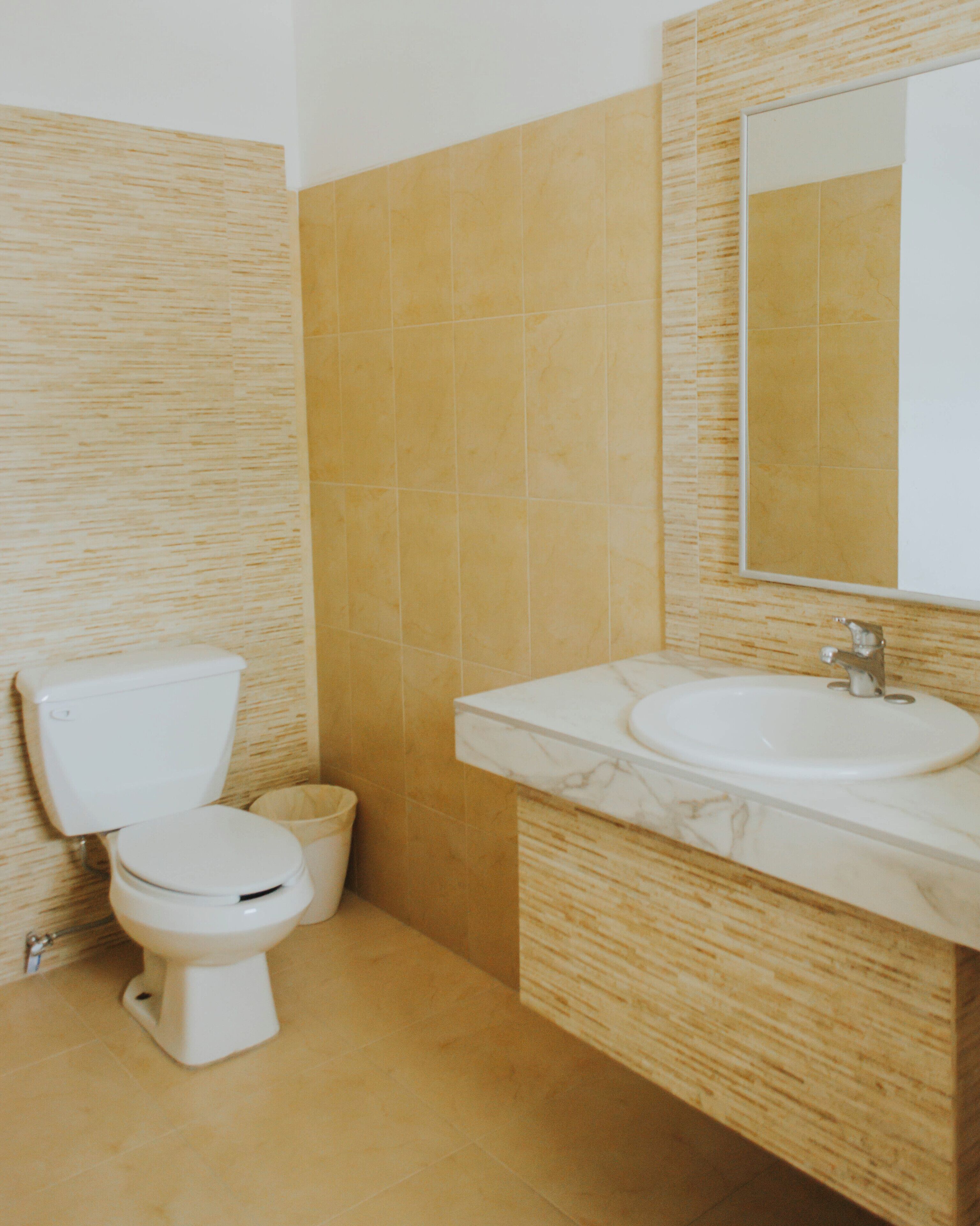 A bathroom with a toilet, sink, and mirror.