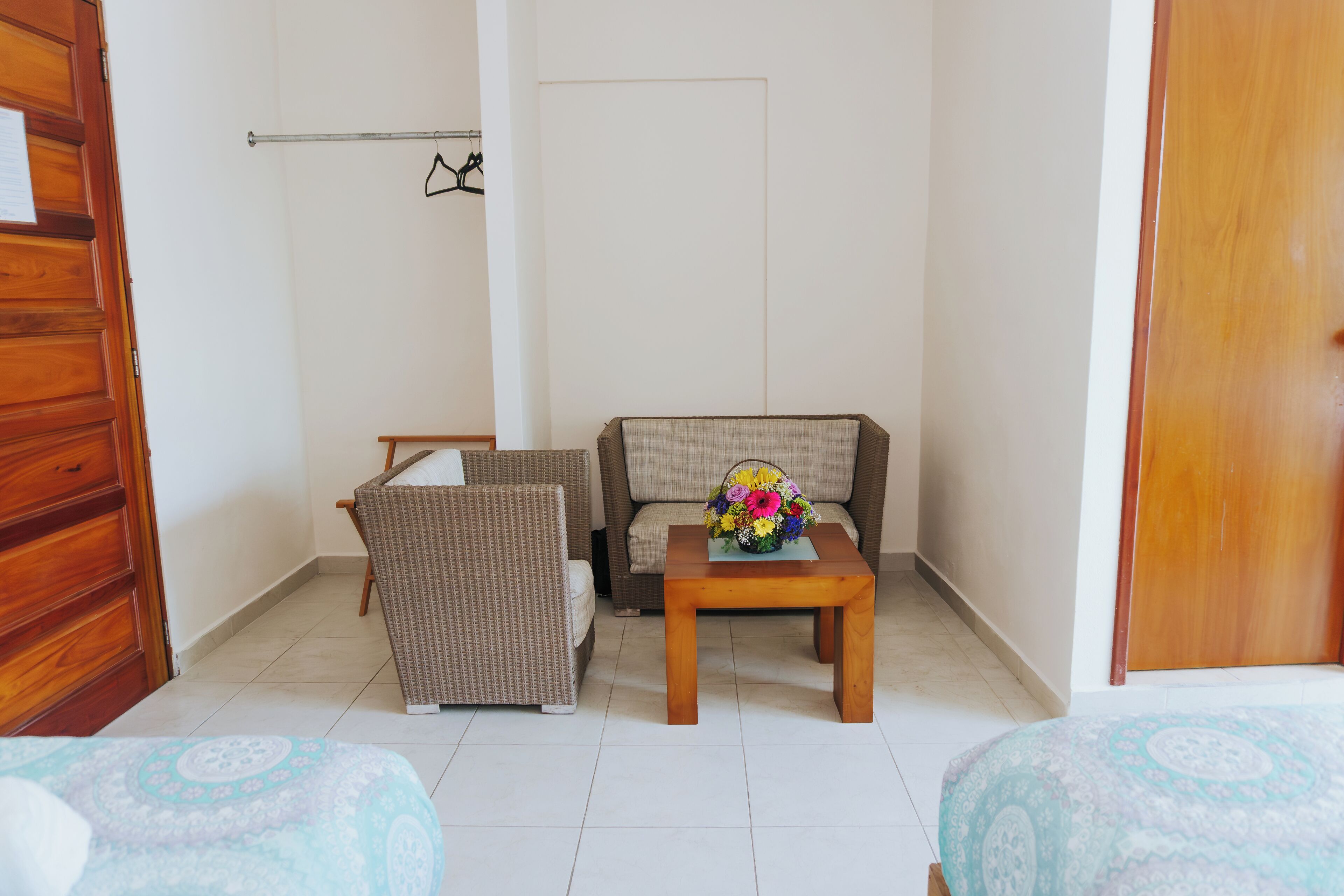 A room with two beds, a wooden dresser, a sofa, and a small table with a vase of flowers.