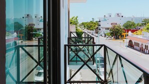 Varanda com guarda-corpo de vidro com vista para uma rua com carros e edifícios.