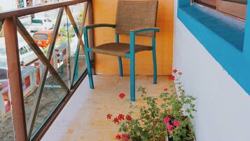 Un balcon avec une chaise, un pot de fleurs et une vue sur la rue.
