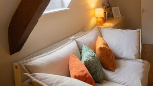 A cozy attic bedroom with a sloped ceiling, a window, a radiator, and a bedside table with a lamp and books. - Countryside Loft in the heart of Bridgnorth (Bridgnorth)