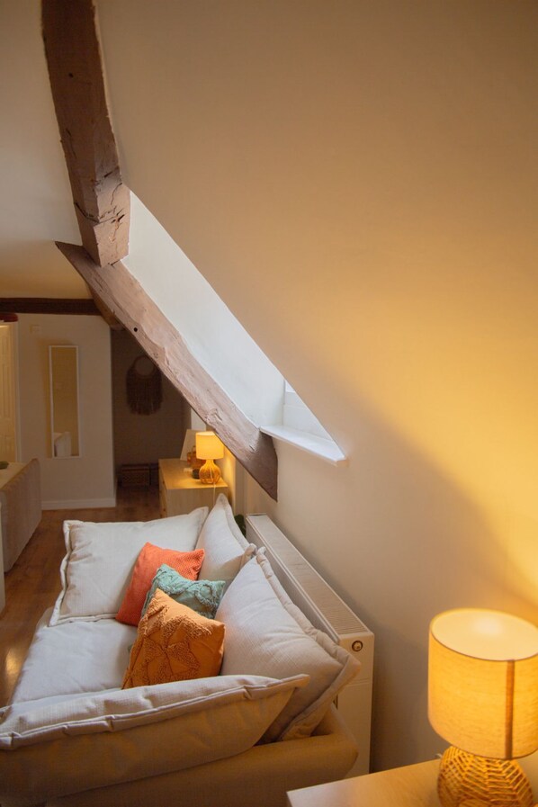 A cozy room with a wooden beam ceiling, a cushioned bench, and a lamp. - Countryside Loft in the heart of Bridgnorth (Bridgnorth)