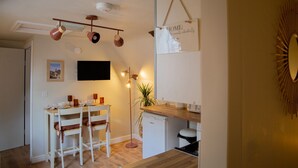 A compact kitchen with a dining area, a TV mounted on the wall, and a sign that says "HOME". - Countryside Loft in the heart of Bridgnorth (Bridgnorth)