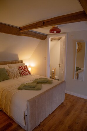 A bedroom with a wooden ceiling, a bed with a white mattress and green pillows, a bedside lamp, and a mirror on the wall. - Countryside Loft in the heart of Bridgnorth (Bridgnorth)