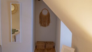 A room with wooden flooring, a mirror, a wall-mounted decorative item, and a table with a basket and a small container. - Countryside Loft in the heart of Bridgnorth (Bridgnorth)