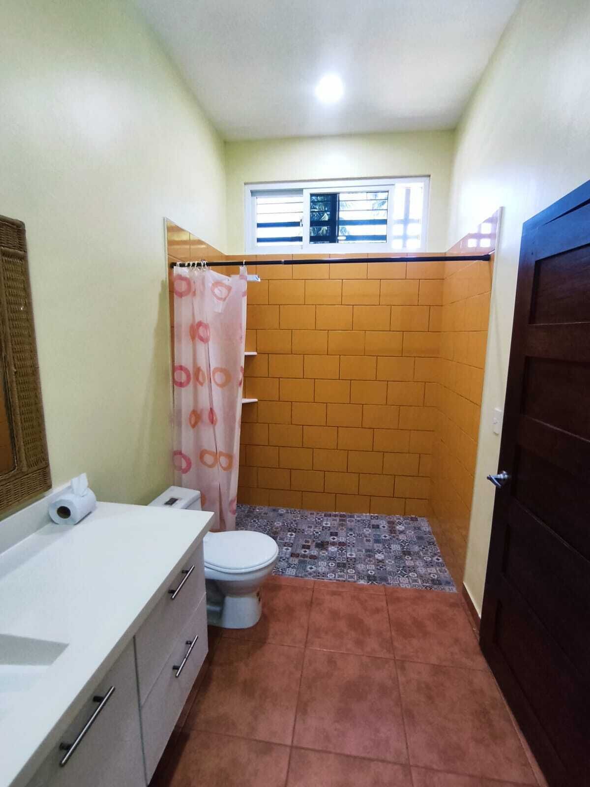 Een kleine badkamer met toilet, wastafel en douchegordijn.