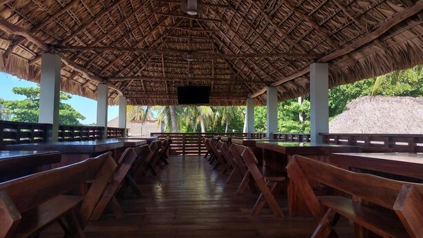 An outdoor dining area with wooden benches and a thatched roof. - Hotel Fragatta playa el cuco  (El Cuco)