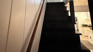 Eine Treppe mit einem hölzernen Geländer, die zu einer Tür am oberen Ende führt.