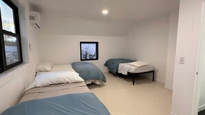 Ein Zimmer mit zwei Betten, einem Fenster und einer Deckenleuchte.