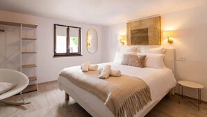 A bedroom with a large bed, a chair, a wardrobe, and a window. - The Cottage (Guémar)
