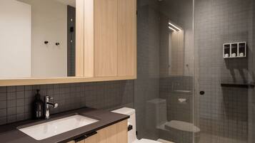 Un bagno moderno con cabina doccia in vetro, un water bianco e un lavabo con piano d'appoggio scuro.