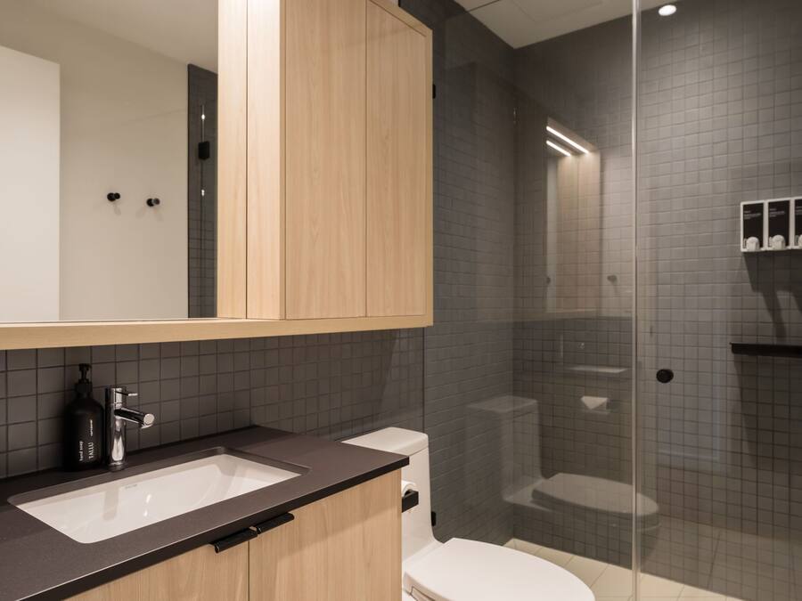 A modern bathroom with a glass-enclosed shower, a white toilet, and a sink with a dark countertop.