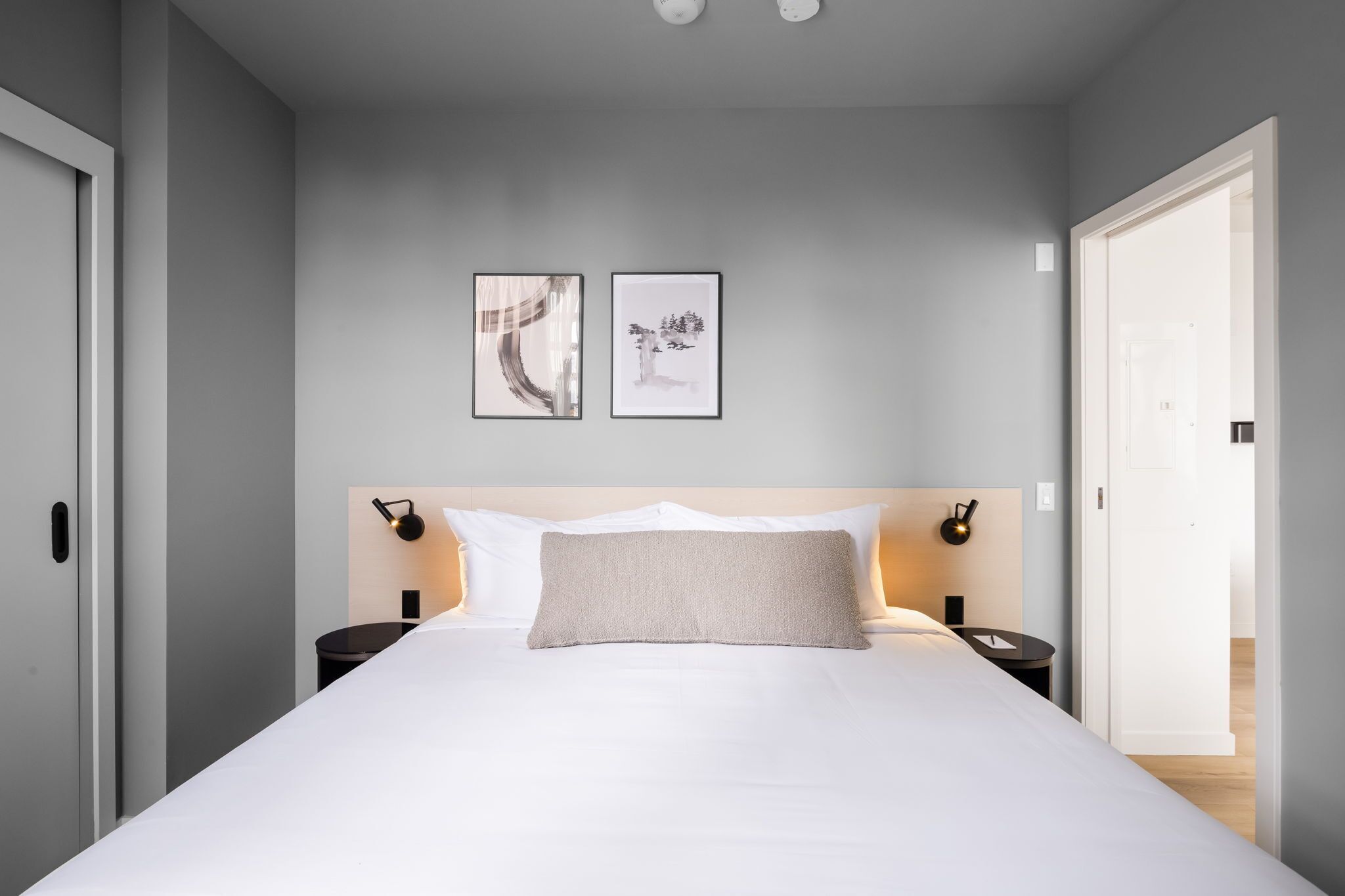Un dormitorio moderno con una cama grande, dos mesitas de noche y una obra de arte enmarcada en la pared.