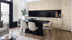A modern kitchen with a black countertop, wooden cabinets, and a dining area with chairs. - Smithe House (Vancouver)