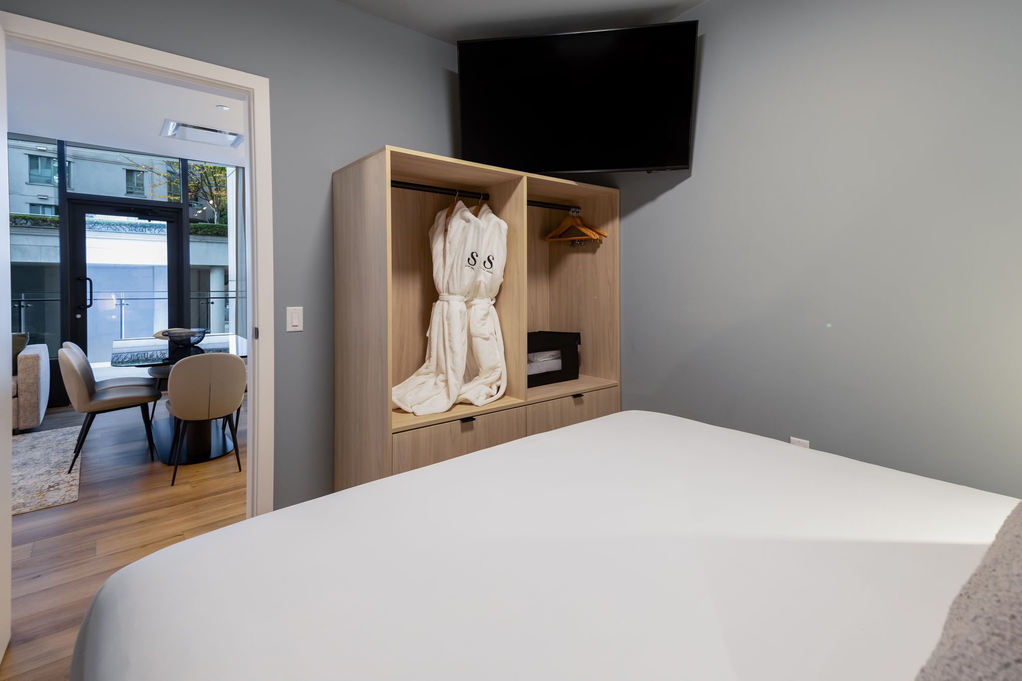 Une chambre d’hôtel moderne dotée d’un grand lit, d’une armoire en bois, d’un téléviseur à écran plat et donnant sur le balcon extérieur.