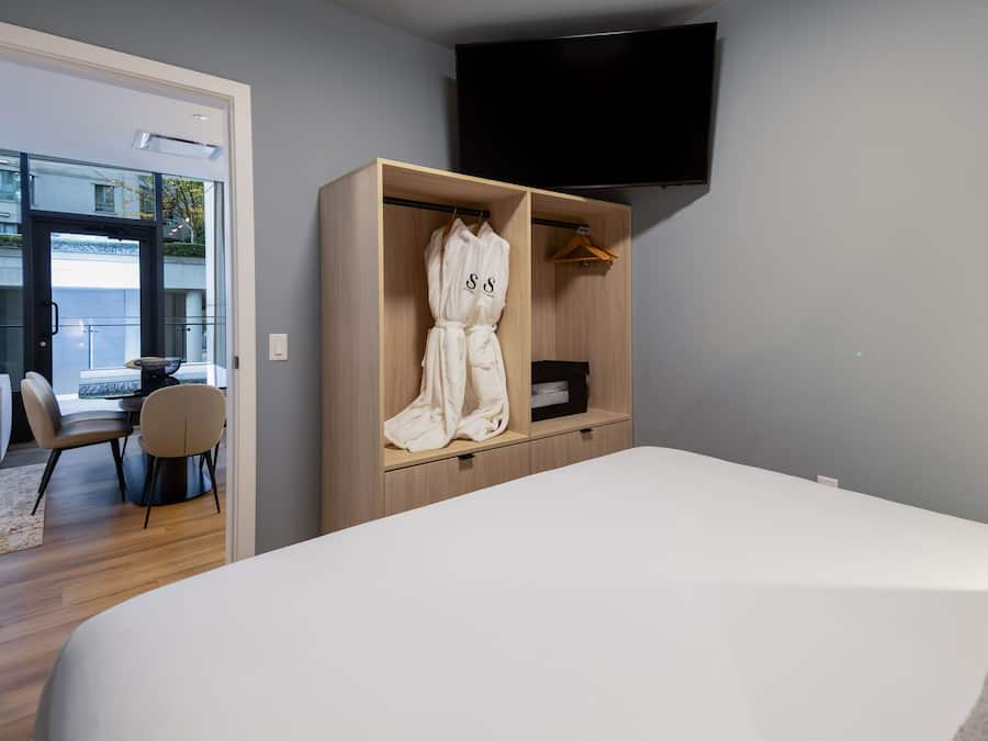 Une chambre d’hôtel moderne dotée d’un grand lit, d’une armoire en bois, d’un téléviseur à écran plat et donnant sur le balcon extérieur.