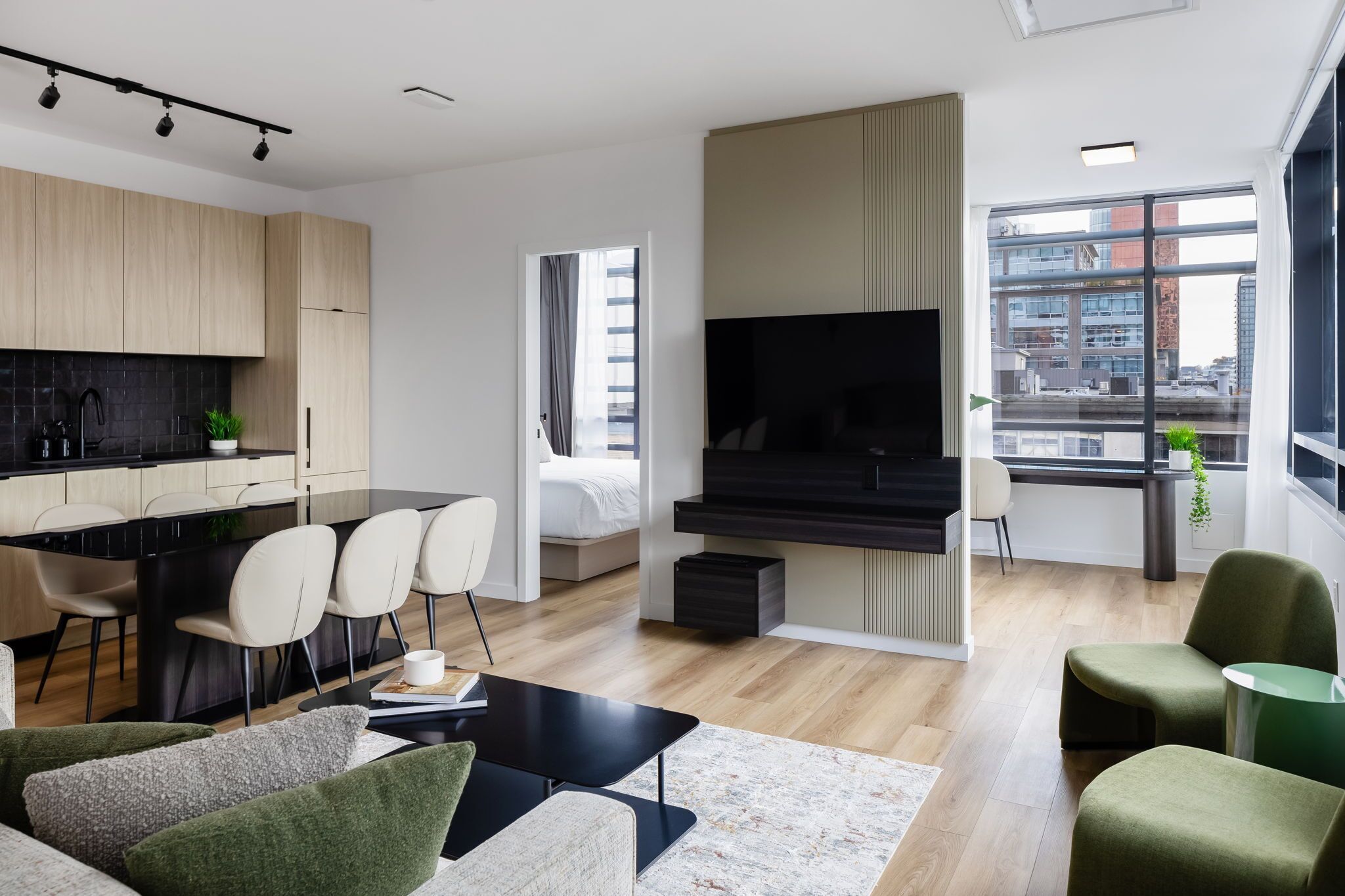A modern living room with a dining area, a kitchen, and a large window with a city view.