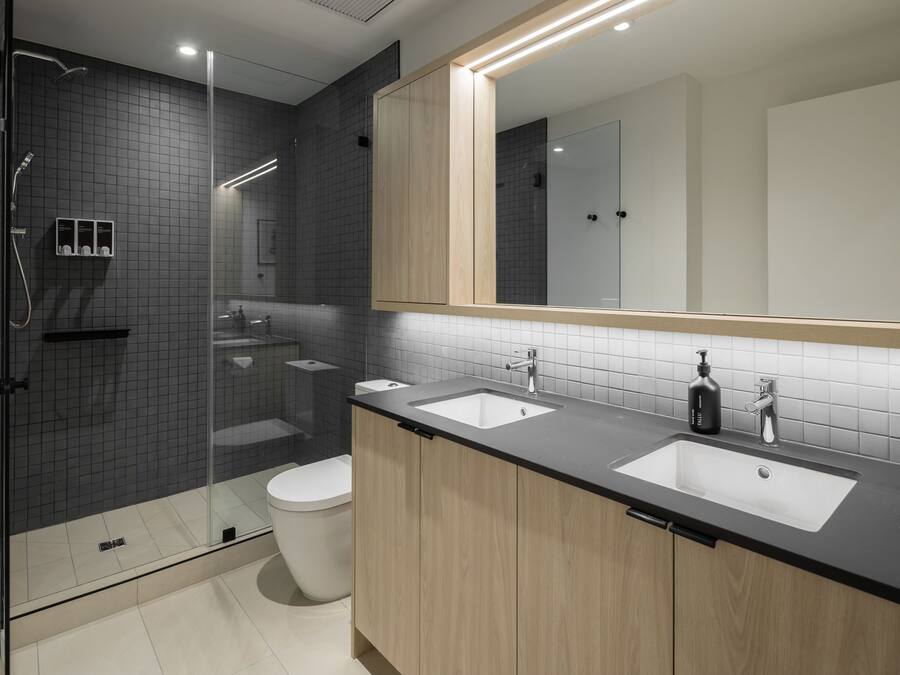 A modern bathroom with a glass shower enclosure, two sinks, and a large mirror.