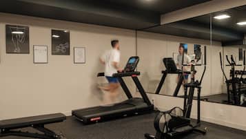 Un gimnasio con cintas de correr, una banca y equipo de ejercicio.