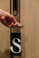 Una mano sosteniendo una llave cerca de una puerta con un aviso de privacidad.