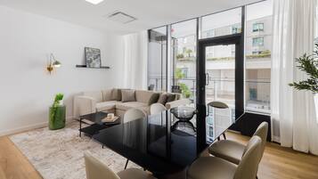A modern living room with a glass door leading to a balcony, a sofa, a dining table, and a coffee table.