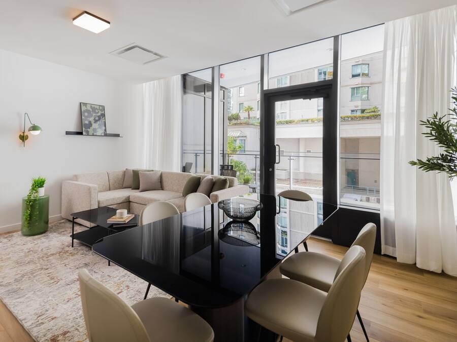 A modern living room with a glass door leading to a balcony, a sofa, a dining table, and a coffee table.